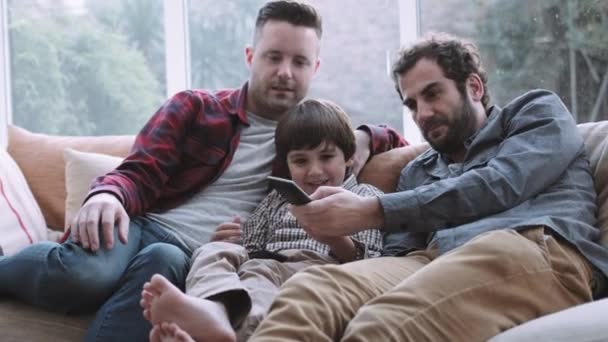 Семья смотрит телевизор на диване — стоковое видео