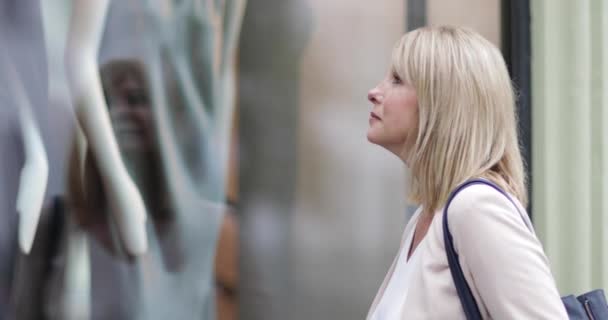 Vrouw Zoekt Een Store Venster — Stockvideo