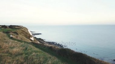 Genç yetişkin kadın cliff üzerinde deniz kenarında çalıştırma dron üzerinden görüntülemek
