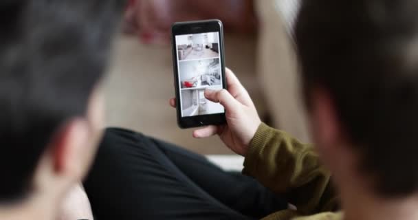 年轻的男性夫妇寻找一个家庭在智能手机应用程序 — 图库视频影像