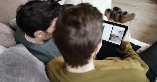 デジタル タブレットの上の家を探している若い男性カップル — ストック動画