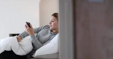 Genç yetişkin kadın uyanma ve smartphone kullanarak