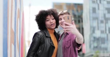 Genç lezbiyen çift renkli duvarın yanında selfie çekiyor.