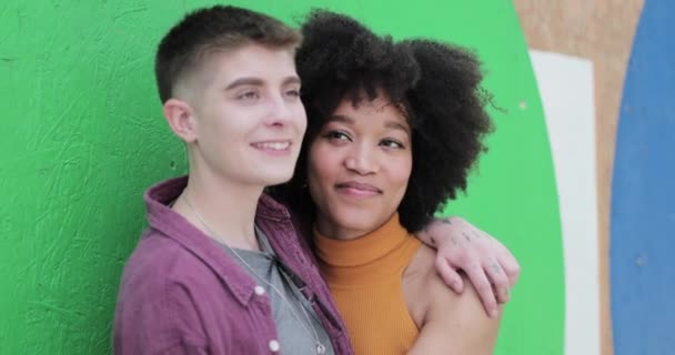 Young adult lesbian couple standing next to green wall Stock Footage