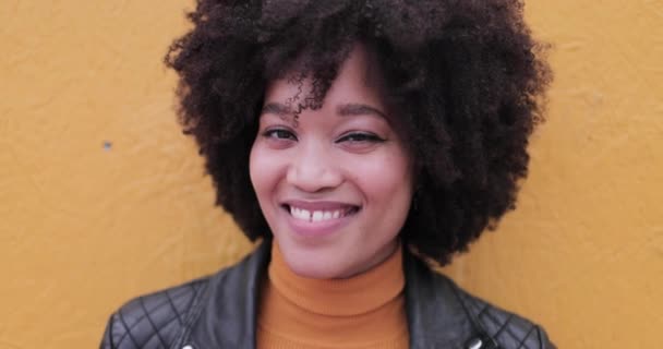 Portrait of African American young adult leaning on bright yellow wall laughing — Stock Video