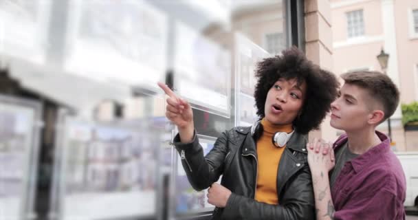 Un couple de lesbiennes regarde la fenêtre des agents immobiliers — Video