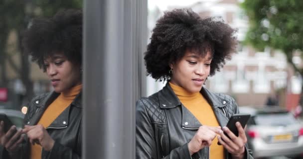 Mujer adulta afroamericana que utiliza teléfonos inteligentes en la ciudad — Vídeos de Stock