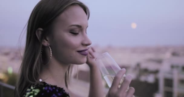 Beyaz kadın kokteyl elbisesi giymiş çatıda şampanya içiyor. — Stok video