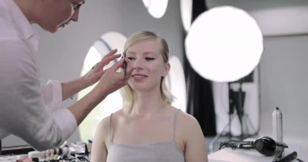 Makeup καλλιτέχνης κάνει μοντέλα eyeliner σε μια φωτογράφηση — Αρχείο Βίντεο