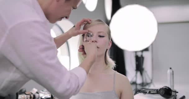 Make-up umělec stočení modelky řasy — Stock video