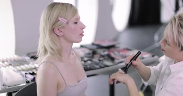 Makeup artist arbetar på en modell på en fotografering — Stockvideo