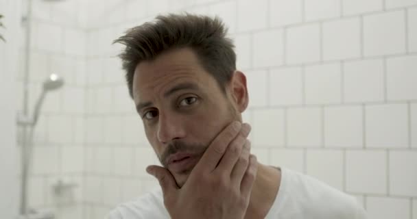 라틴 남자 가 욕실 거울에 비친 턱수염을 확인하는 모습 — 비디오