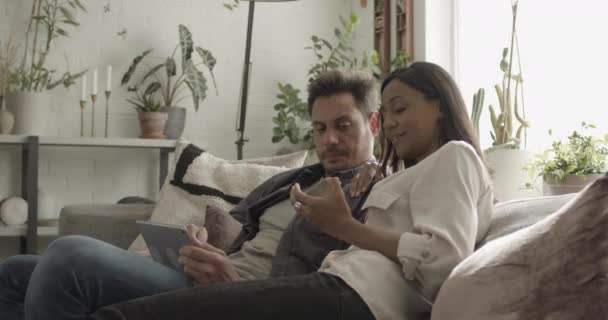 Casal Latino em sofá compra online com cartão de crédito em tablet digital — Vídeo de Stock