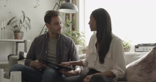 Young adult couple looking at music record at home on sofa — Stock Video