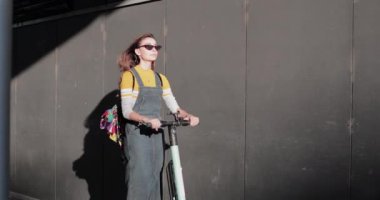 Şehir caddesinde elektrikli scooter kullanan bir kadın.