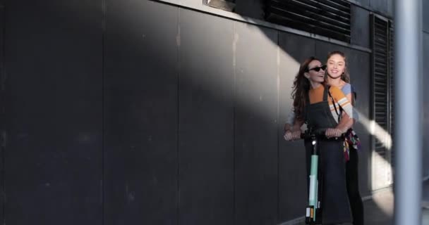Vriendinnen hebben plezier paardrijden elektrische scooter op stedelijke straat — Stockvideo