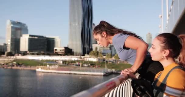 Girlfriends colgando en el puente al atardecer — Vídeo de stock