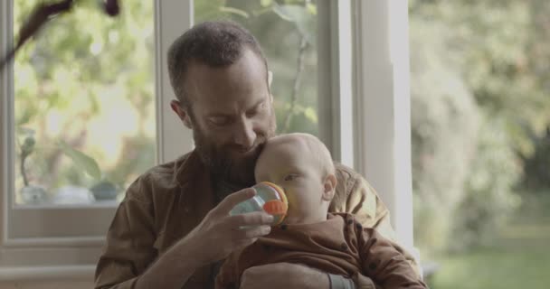 Svobodný otec krmení láhev na dítě syn na klíně — Stock video