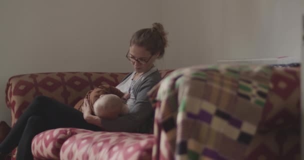 Ανύπαντρη μητέρα θηλάζει μωρό στον καναπέ — Αρχείο Βίντεο