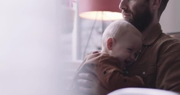 Bekar baba kucağında oturan ağlayan bebeği rahatlatır. — Stok video