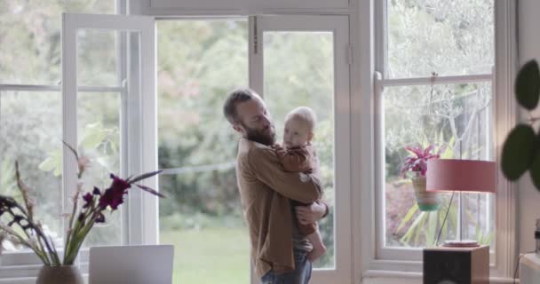 Ensamstående förälder som arbetar hemifrån på smarttelefon och håller barn — Stockvideo