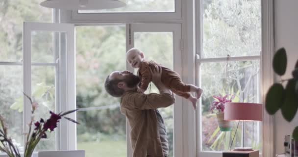 Père célibataire soulevant un bébé et jouant dans un salon — Video