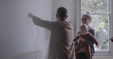 Noel partisi için Noel ışıkları asan çocuklu bir aile.