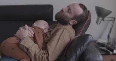 Bekar baba ve bebek oturma odasında kanepede uyur.