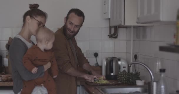 Pai preparando alimentos saudáveis na cozinha com mãe e bebê — Vídeo de Stock