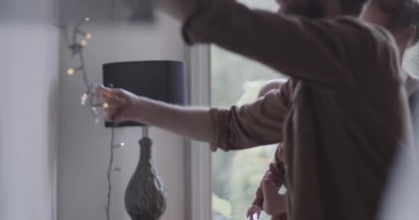 Familie mit Baby hängt Weihnachtsbeleuchtung für Weihnachtsfeier auf — Stockvideo