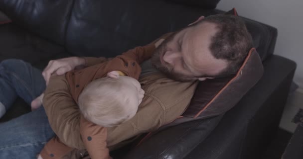 Bekar baba ve bebek oturma odasında kanepede uyur. — Stok video