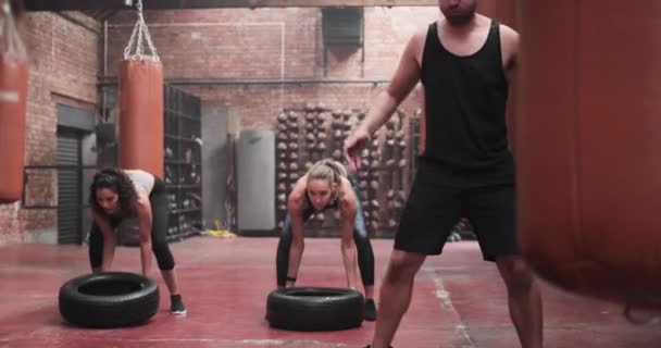 Groupe de personnes retournant des pneus dans un exercice de musculation — Video
