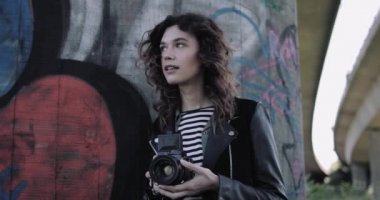Genç yetişkin kadın fotoğrafçı eski kamera ile şehir merkezinde.