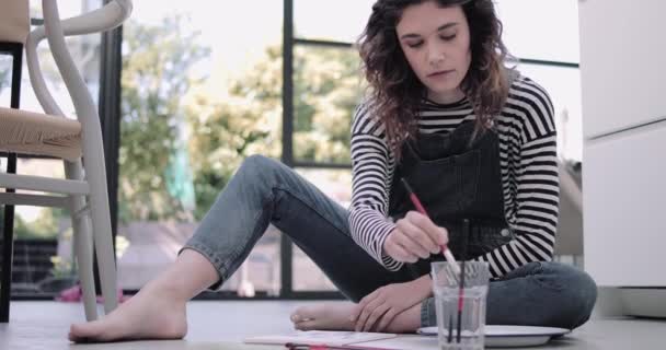 Young adult woman artist on floor painting in studio — Stock Video