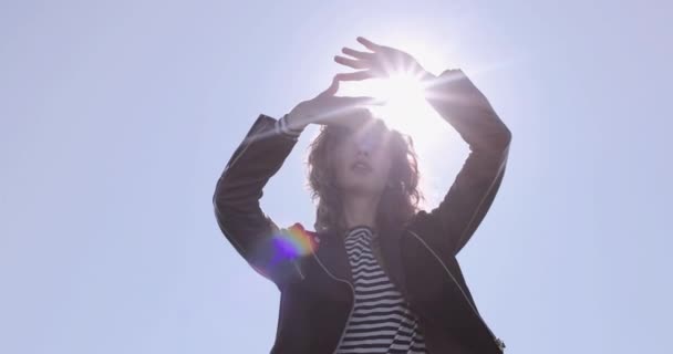 Fiatal felnőtt nő néz vályú kezek az égen a nap mögött