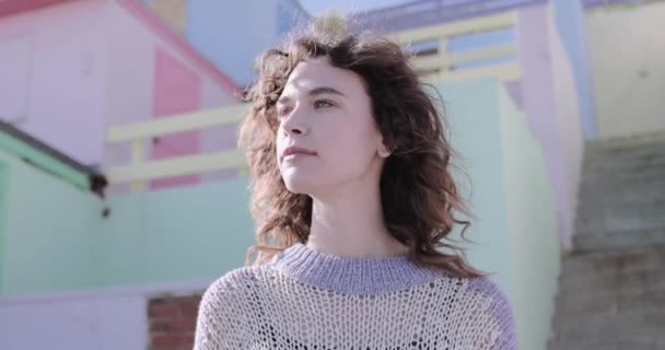 Pretty young adult woman standing near colourful beach hut — Stock Video