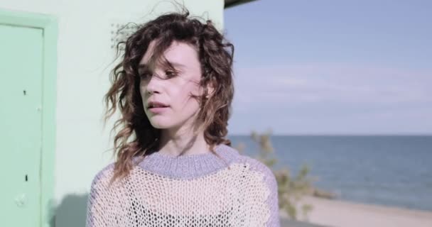 Pretty young adult woman standing near colourful beach hut — Stock Video