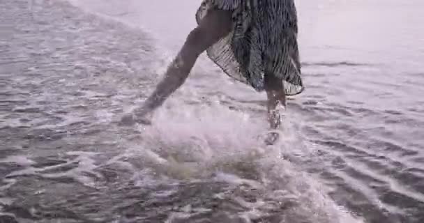 Young adult woman splashing water in the sea in dress — Stok Video