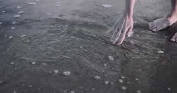Закрытие женщины, играющей рукой с водой в море — стоковое видео