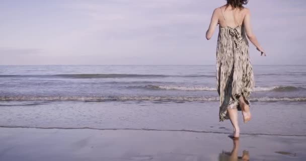 Mujer adulta joven que entra en el mar vestida — Vídeo de stock