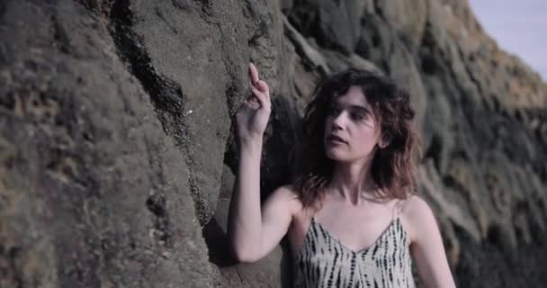 Genç bir kadın deniz kenarındaki kayalara dokunuyor. — Stok video