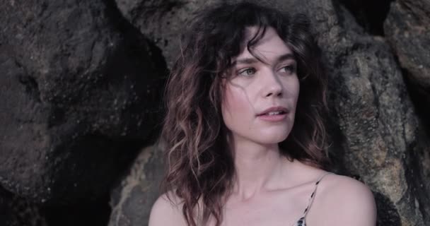 Портрет молодой взрослой женщины, прислонившейся к камням — стоковое видео