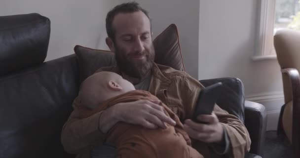 Отец-одиночка делает селфи с маленьким сыном на диване — стоковое видео