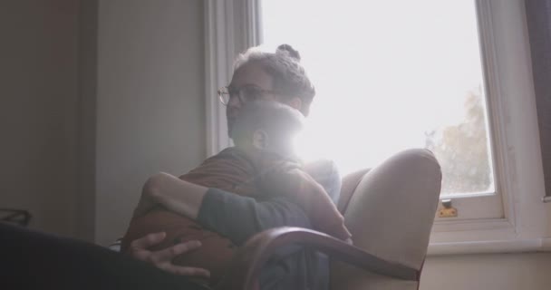 Ενιαία μητέρα παρήγορο μωρό κάθεται στην καρέκλα στο σαλόνι — Αρχείο Βίντεο