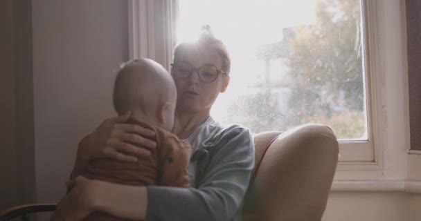 Alleenstaande moeder troostende baby zitten op stoel in woonkamer — Stockvideo