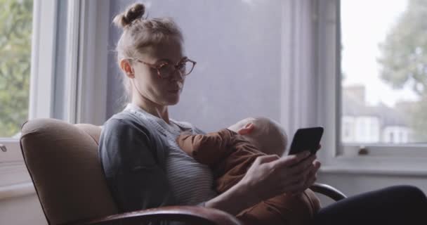 Ενιαία μητέρα παρήγορο μωρό και να εξετάσουμε έξυπνο τηλέφωνο — Αρχείο Βίντεο
