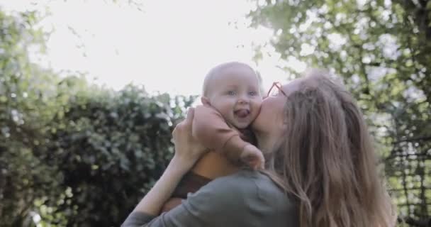 单身母亲在花园里抱孩子，在阳光下玩耍 — 图库视频影像