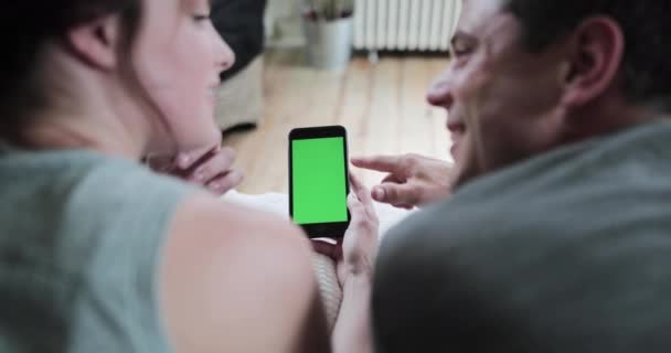 Casal adulto jovem olhando para um smartphone juntamente com tela verde — Vídeo de Stock