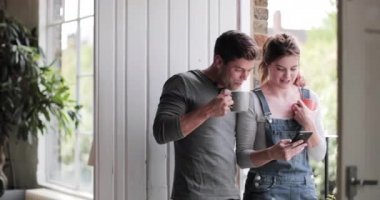 Genç çiftler sabah kahvelerini içip akıllı telefonları kontrol ediyorlar.