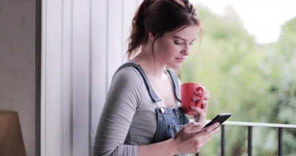 Jong volwassen vrouw met ochtend koffie en het controleren van smartphone — Stockvideo
